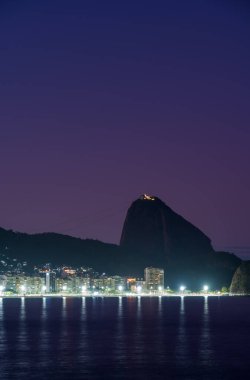 Copacabana Sahili 'nde gün batımı fotoğrafı ipeksi su efekti ve mor gökyüzü, Sugarloaf Dağı.