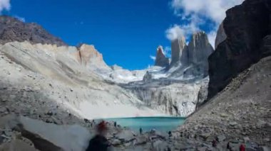 Bir zaman çizelgesi Torres del Paine 'de dağların üzerinde bulutlar ve buzul gölü olan insanları gösteriyor..