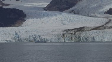 Tourists on a boat observe the immense Spegazzini Glacier in Argentina, appreciating the grandeur of nature. clipart