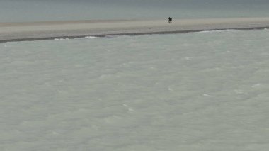 Çift buzlu sular arasında ince sahilde yürüyor, ağır çekimde yakalanıyor..