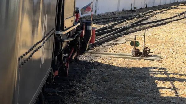 stock image Side view of an old steam train departing the station, with visible steam and moving parts.