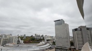 Gökdelenlerin zamanlaması ve bir apartman penceresine yansıyan bir stadyum akşam karanlığına dönüşürken, bulutlar açık bir gökyüzünü ortaya çıkarıyor..