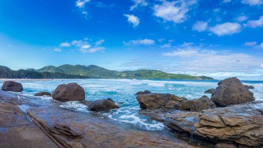 Turkuaz denizi ve berrak mavi gökyüzünün altında yemyeşil dağları olan el değmemiş bir sahil..