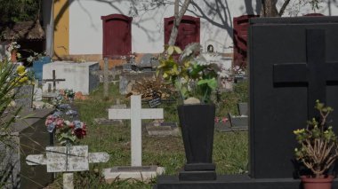 Mezar taşları, yeşil çimenler ve haçlarla dolu, telefoto merceğiyle çekilen ve çeşitli derinlikleri gösteren huzurlu bir mezarlığın ek video turu..