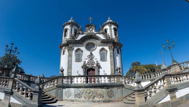 Süslü bir cephesi ve ikiz kuleleri olan Barok tarzı bir kilise mavi gökyüzüne karşı duruyor..
