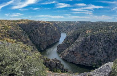 Engebeli uçurumlar ve yemyeşil yemyeşil, berrak mavi bir gökyüzünün altında nefes kesici bir nehir vadisi..