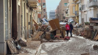 2 Kasım 2024 'te Benetuser, Valencia, İspanya' da insanlar DANA sel felaketinin yol açtığı tahribatın ardından çamurlu caddelerde ve hasarlı araçlarda geziniyorlar..