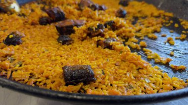 A video features a freshly made paella being served onto plates, with a fork taking a portion in the foreground. clipart