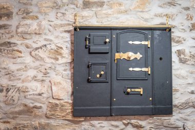 Tarihi işçilik ve mimari zarafeti vurgulayan, taştan bir duvarda karmaşık bir tasarımı olan klasik bir demir kapı..