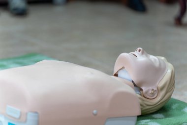 Acil hayat kurtarma eğitimi için kullanılan yeşil bir paspasın üzerinde suni teneffüs mankeni yakın plan..