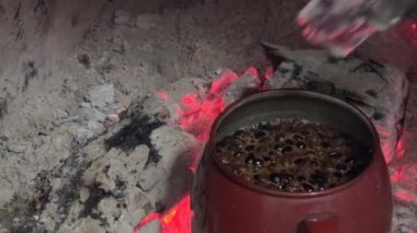 Bir video, geleneksel otantik çaydanlık kahvesi yapma yöntemini gösteriyor. Yanan bir odun parçasını bir demlik suya yerleştirerek..