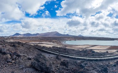 Lanzarotes 'un panoramik manzarası tuz düzlükleri, Kanarya Adaları dramatik bir gökyüzünün altındaki volkanik araziyi gösteriyor..