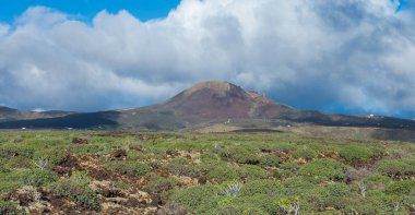 Bereketli yeşillik ve çarpıcı bulutlu gökyüzü ile çarpıcı bir volkanik manzara dokunulmamış doğanın güzelliğini gösteriyor..