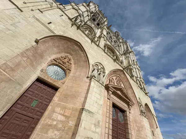Karmaşık detayları ve yükselen kemerleri olan Gotik bir katedral parlak mavi gökyüzünün altında görkemli bir şekilde duruyor..