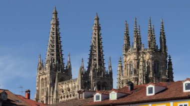 Burgos Katedrali 'nin havadan görünüşü, ön planda şehir çatılarının bulunduğu açık mavi gökyüzünün altındaki gotik mimarisini ön plana çıkarıyor..