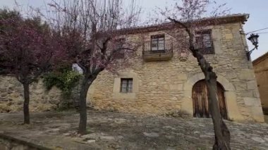 Büyük antik bir taş ev çiçek açan ağaçlarla süslenir, güzelliğini ve zarafetini ön plana çıkarır..