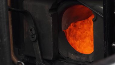 İtfaiyeci, yanan bir buhar trenine kömür atar. Operasyon sırasında açık fırından görülebilen yoğun alevler..