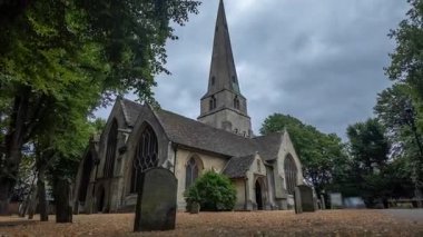 Alçak açılı zaman çizelgesi, yüksek kulesi ve antik mezarlığı olan İngiliz Gotik kilisesini gösteriyor. Kamera gökyüzüne doğru hareket ediyor..
