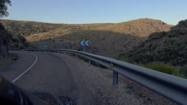 Bir araç derin bir kanyon ve nehrin üzerindeki çarpıcı metal kemer köprüsünün yanında mühendislik becerisi ve bağlantısını vurguluyor..