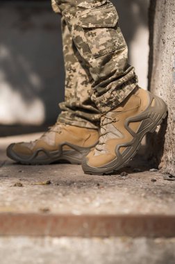 Özel üniformalı ve koruyucu taktik spor ayakkabılı bir asker. Haki ve yeşil giysili askerler için su geçirmez spor ayakkabılar.