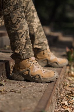 Özel üniformalı ve koruyucu taktik spor ayakkabılı bir asker. Haki ve yeşil giysili askerler için su geçirmez spor ayakkabılar.