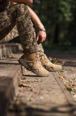 Özel üniformalı ve koruyucu taktik spor ayakkabılı bir asker. Haki ve yeşil giysili askerler için su geçirmez spor ayakkabılar.