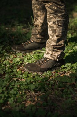 Özel üniformalı ve koruyucu taktik spor ayakkabılı bir asker. Haki ve yeşil giysili askerler için su geçirmez spor ayakkabılar.