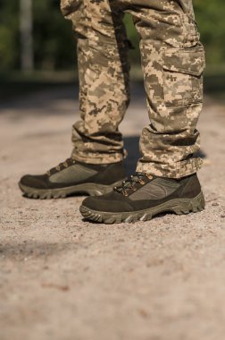 Özel üniformalı ve koruyucu taktik spor ayakkabılı bir asker. Haki ve yeşil giysili askerler için su geçirmez spor ayakkabılar.