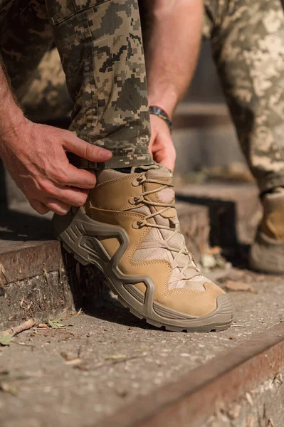 A military man in a special uniform and protective tactical sneakers. Special waterproof sneakers for soldiers in khaki and green