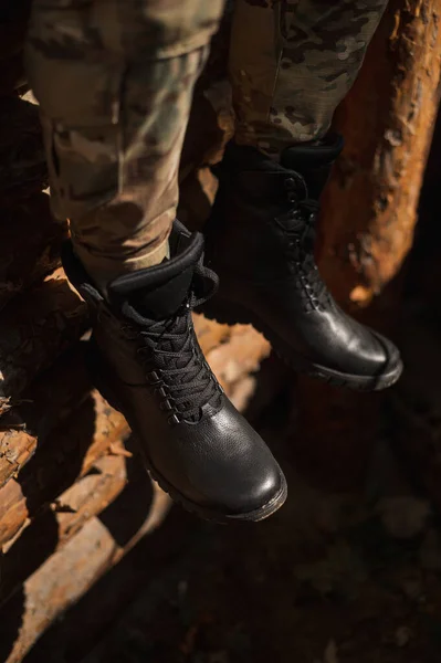 A military man in high black lace-up leather sneakers in a trench