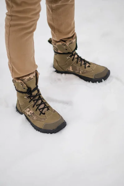 Dark green winter leather military boots. A soldier walks in boots in the snow