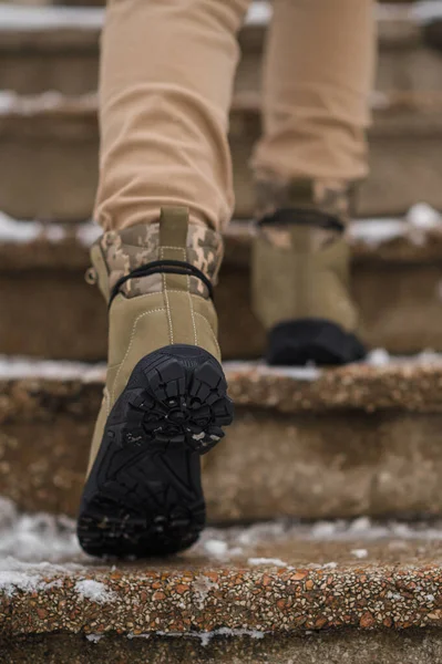 Dark green winter leather military boots. A soldier walks in boots in the snow