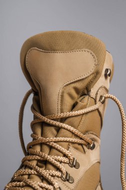 Gri arka planda haki rengi yüksek askeri botlar.