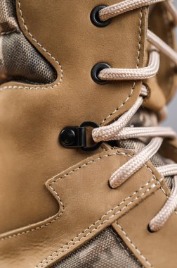 Gri arka planda haki rengi yüksek askeri botlar.