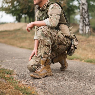 Savaş meydanında taktik sırt çantası taşıyan özel üniformalı bir asker.