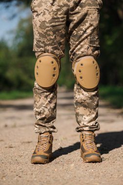 Koruyucu üniformalı asker. Koruyucu kamuflaj üniforması. Askerler için dirseklikler ve dizlikler.