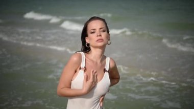 Bir kadın güzel okyanusun kıyısında zarif pozlar verir. Etrafında plaj titreşimleri, zarafet ve saf dinginlik sergiler.