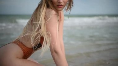 Bir manken kumlu sahilde zarifçe poz verir, dingin sahil havasını ve yaz zarafetini yakalar.