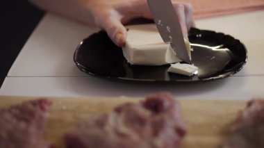 Bir şef, yumuşak krem peyniri dilimliyor. Mutfak sanatını ön plana çıkaran lezzetli bir yemek için karmaşık bir hazırlık yapıyor.