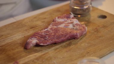 Kaba bir tahtanın üzerinde lezzetli bir parça et tatlandıran yetenekli bir insan, pişirmeye hazır.
