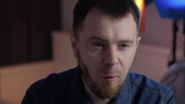 Düşünceli bir adam çağdaş bir ortamda oturur, derin, derin duyguları yansıtır ve poz verir.