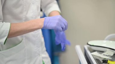 Bir sağlık görevlisi, güvenlik ve hijyen için koruyucu eldiven ve ekipman takarak bir prosedüre hazırlanır.