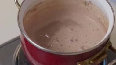 Sıcak bir sobada ustalıkla karıştırılan ve yakında servis edilmeye hazır bir tencere dolusu sıcak çikolata.