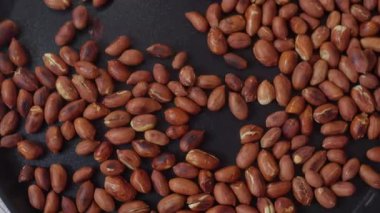 Kavrulmuş fıstıkların kızartma tavasında nazikçe karıştırılıp çıtır çıtır ve lezzetli bir atıştırmalık yarattığı yakın çekim görüntüsü.