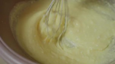 Güzelce pürüzsüz bir kek hamurunun karıştırma kabında enerjiyle çırpılmasının yakın plan görüntüsü, pişirmek için ideal.