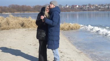 Sevgi dolu bir çift, doğanın ihtişamıyla çevrili sakin bir sahilde romantik bir öpücük paylaşıyor.