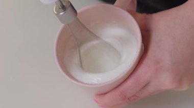 Büyüleyici pembe bir fincanın içinde ustaca çırpılmış krema, enfes bir modern mutfak anı sergiliyor.