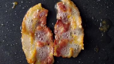 Altın pastırma dilimleri sıcak bir tavada cızırdıyor, herkes için ağız sulandıran bir kahvaltı sahnesi oluşturuyor.