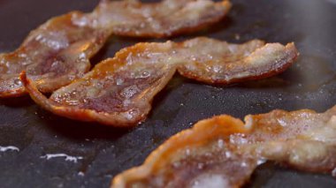 Lezzetli çıtır pastırma dilimleri şimdi sıcak bir ızgarada cızırdıyor. Nefis bir kahvaltı için mükemmeller.
