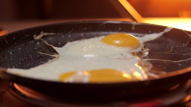 İki mükemmel güneşli yumurta kızartma tavasında pişiriliyor, lezzetli cızırtıyı ve zengin dokuyu yakalıyorlar.